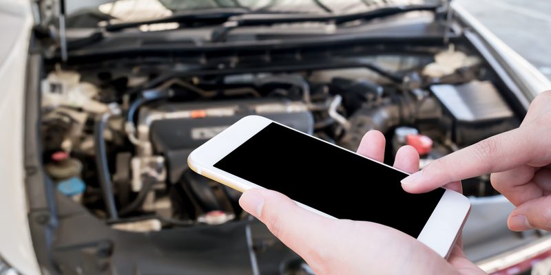 woman using mobile phone with broken down car