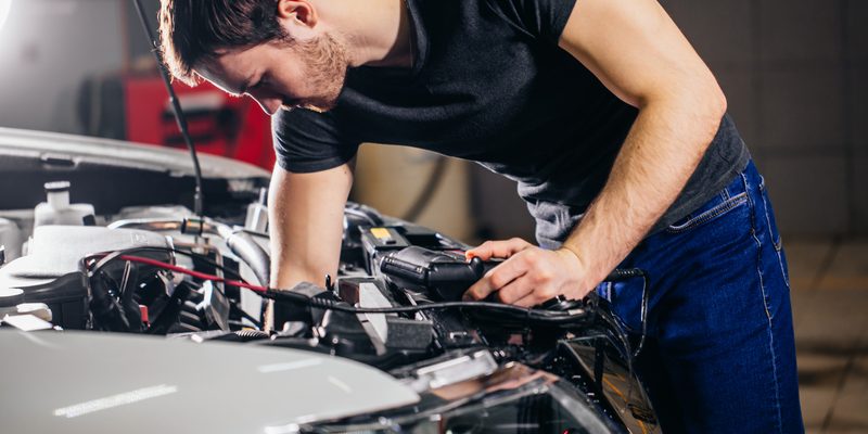 mechanic testing electrical system on automobile